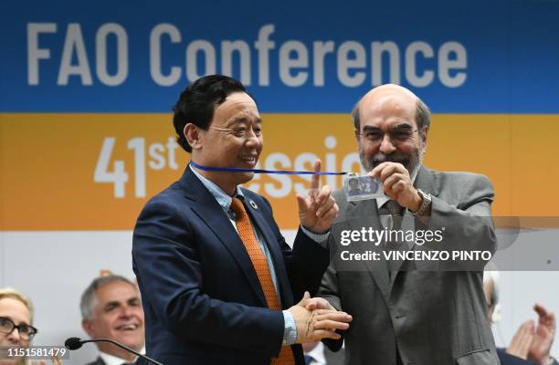 Outgoing FAO Director-General, Jose Graziano da Silva holds the badge of newly-appointed FAO Director-General, China's Qu Dongyu on June 23, 2019...