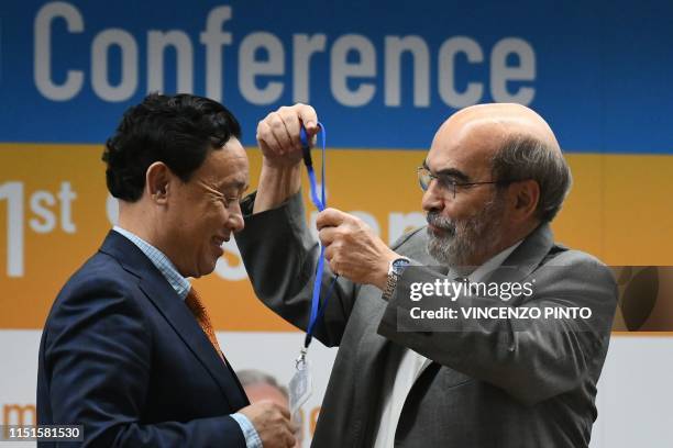 Outgoing FAO Director-General, Jose Graziano da Silva puts the badge of Director-General elect around the neck of newly-appointed FAO...
