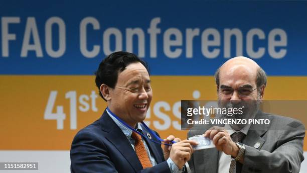 Outgoing FAO Director-General, Jose Graziano da Silva holds the badge of newly-appointed FAO Director-General, China's Qu Dongyu on June 23, 2019...