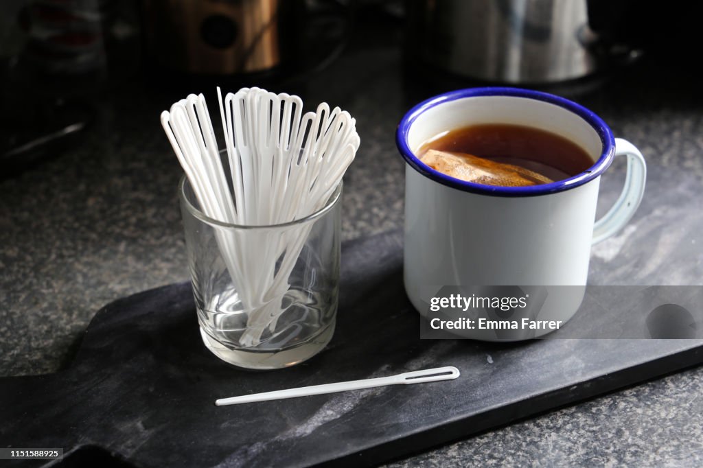 Plastic drink stirrers next to mug of tea