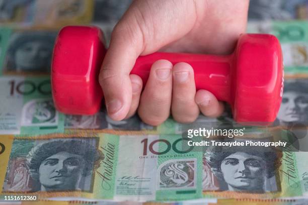australian currency in the background along with a human hand holding a hand weight. - 100 stock pictures, royalty-free photos & images