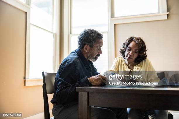 senior couple paying bills at home - mann am tisch mit papier stock-fotos und bilder