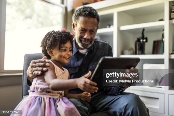 Granddaughter showing grandfather how to use tablet