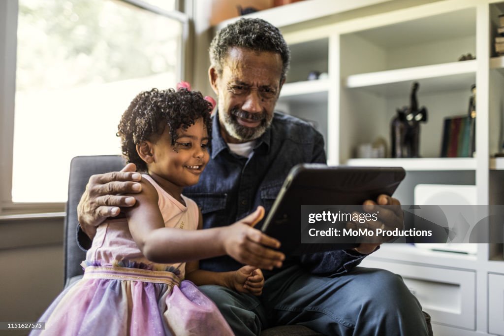 Granddaughter showing grandfather how to use tablet
