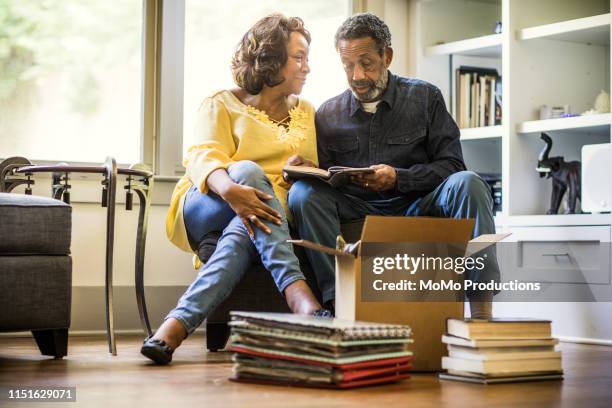 senior couple packing books to move - interracial wife fotos stockfoto's en -beelden