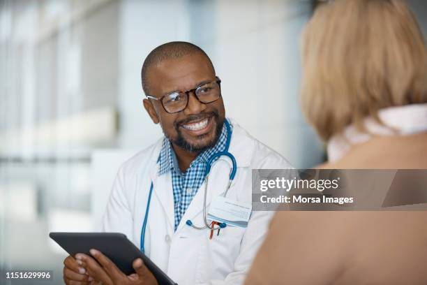 male doctor with digital tablet looking at woman - male doctor man patient stock-fotos und bilder