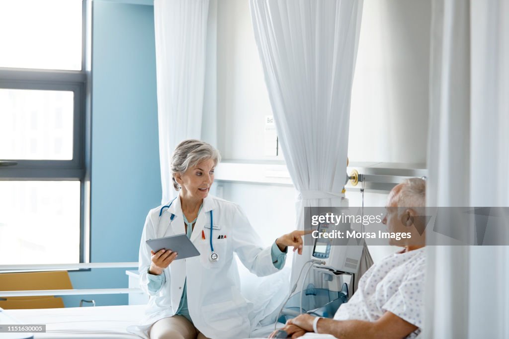 Female doctor pointing at medical equipment to man