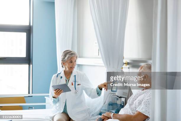 female doctor pointing at medical equipment to man - bedside manner stock pictures, royalty-free photos & images