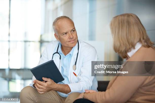 doctor with digital tablet looking at woman - dr visit stock pictures, royalty-free photos & images