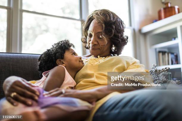 grandmother and granddaughter cuddling on couch - grandmas living room photos et images de collection