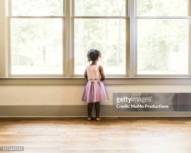 portrait of preschool age girl looking out window - girl black dress stock pictures, royalty-free photos & images