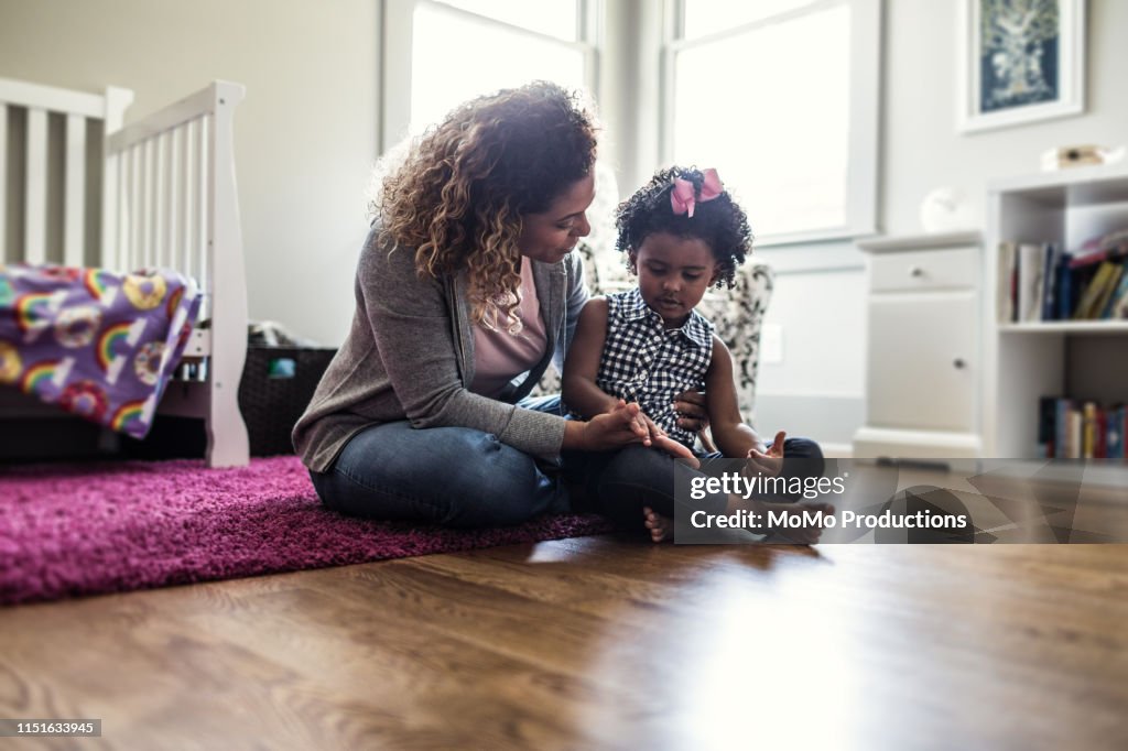 Mother and daughter playing on bedroom floor