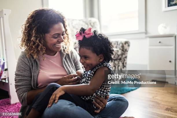 mother and daughter playing on bedroom floor - latin single mother stock pictures, royalty-free photos & images