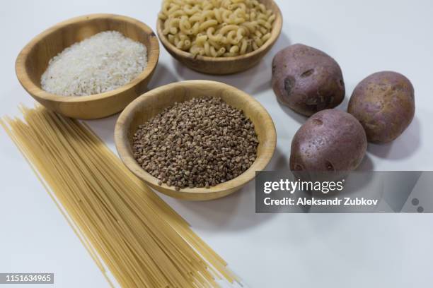 group of carbohydrates for diet - bread, rice, potatoes and pasta on a wood table in the background - carbohidrato fotografías e imágenes de stock