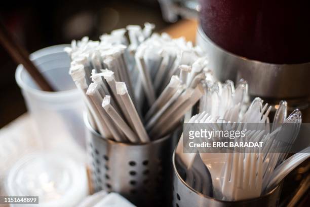 Plastic straws wrapped in paper and plastic forks are seen at a food hall in Washington DC on June 20, 2019. - "How do you drink a milkshake without...