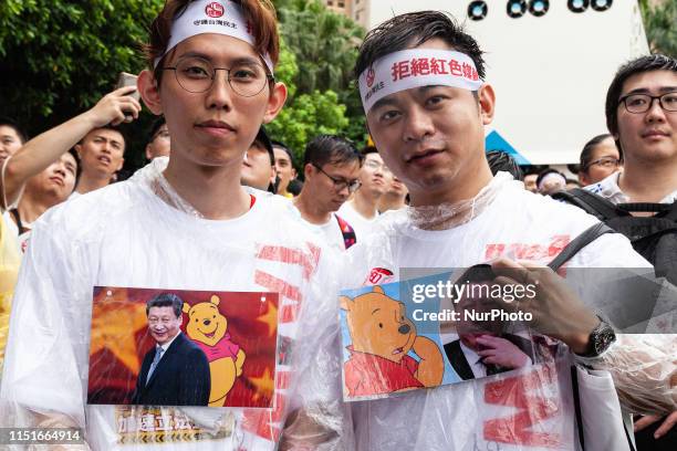 Protesters standing in the heavy rain wearing t-shirts representing The President of the People's Republic of China President Xi Jinping together...