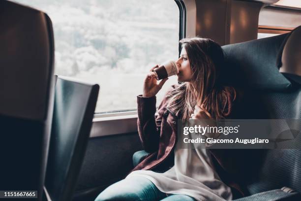 young woman drinking a hot drink on tgv train, paris, france, europe - station service france stock-fotos und bilder