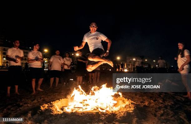 Man jumps over a bonfire during the annual San Juan celebrations on a beach in Alicante, Valencia, on June 23, 2019. - Fires are lit throughout Spain...