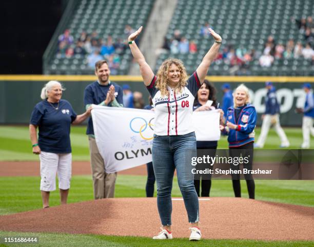 Former Olympian Margaret Hoelzer celebrates in front of fellow Olympians after throwing out the ceremonial first pitch before a game between the...