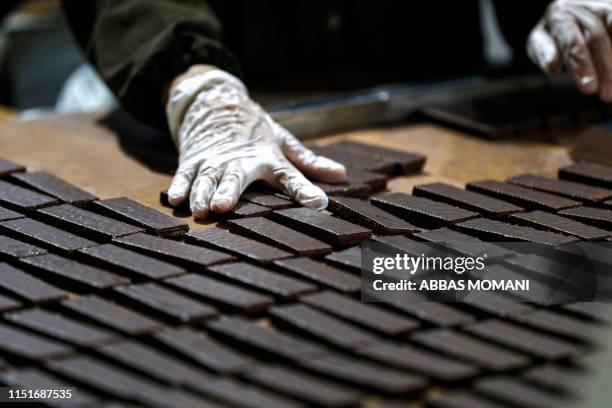 Palestinian industrial workers wrap freshly-produced chocolate wafer biscuits before packing at a factory in the West Bank city of Ramallah on June...