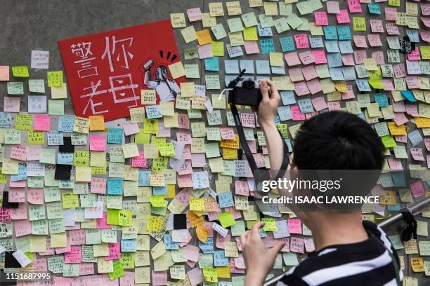 This picture taken on June 22, 2019 shows a man taking photographs of artwork and messages in support of protesters opposed to a China extradition...