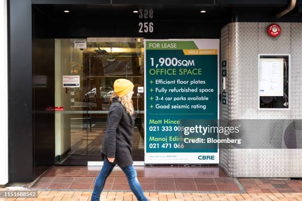 Pedestrian walks past a "For Lease" sign for an office space outside a building in Wellington, New Zealand, on Saturday, June 22, 2019. The...