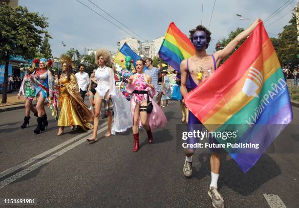 Participants in fancy costumes carry rainbow flags down a street during the KyivPride 2019 Equality March held in support of the LGBT community,...