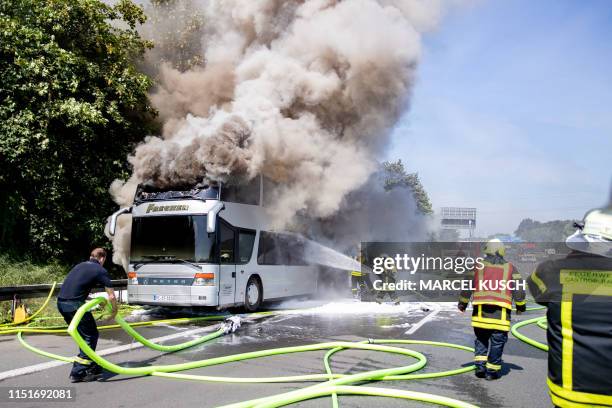 Firemen extinguish a burning touring coach on the A2 highway in Castrop-Rauxel, western Germany, on June 24, 2019. - The bus with 65 pupils on board...