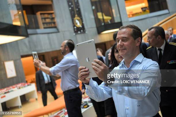 French Prime minister Edouard Philippe and his Russian homolog Dimitri Medvedev hold tablets as they visit the Oscar Niemeyer library during an...