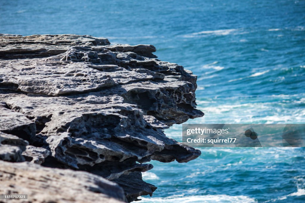 Oceanside rocky cliff top with blue coastal sea in background