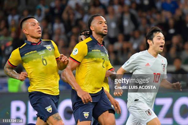 Ecuador's Cristian Ramirez and Arturo Mina and Japan's Shoya Nakajima run during their Copa America football tournament group match at the Mineirao...