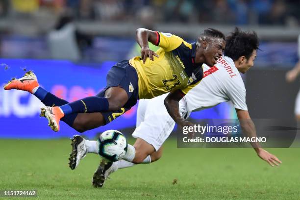 Ecuador's Jhegson Sebastian Mendez and Japan's Gaku Shibasaki fall during their Copa America football tournament group match at the Mineirao Stadium...