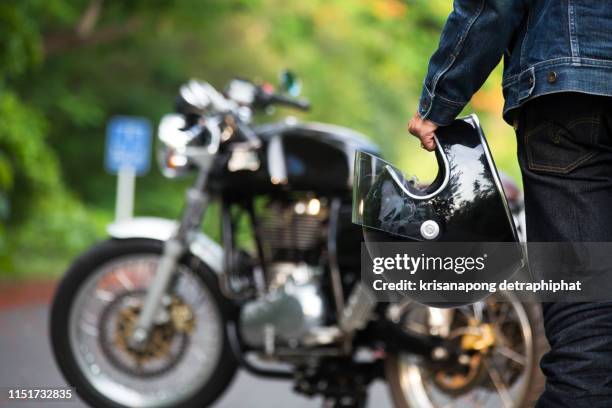 hand man holding a helmet and  motorcycle blur background. - motociclista fotografías e imágenes de stock