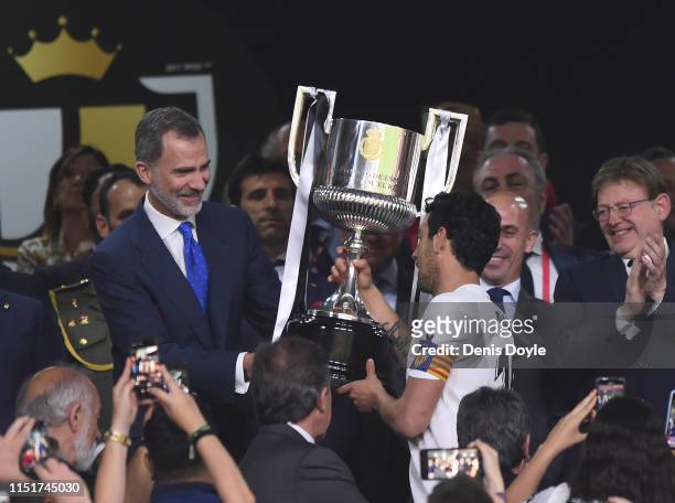 King Felipe VI of Spain hands Dani Parejo of Valencia CF the Copa del Rey trophy at the end of the Spanish Copa del Rey final between Barcelona and...