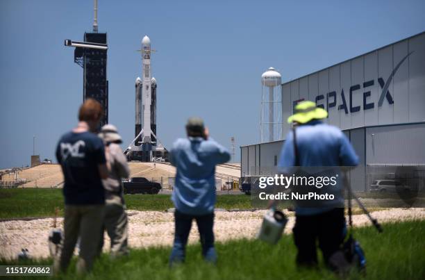 Media members take photographs of a SpaceX Falcon Heavy rocket carrying satellites for the U.S. Air Force as it stands ready for launch tonight at...