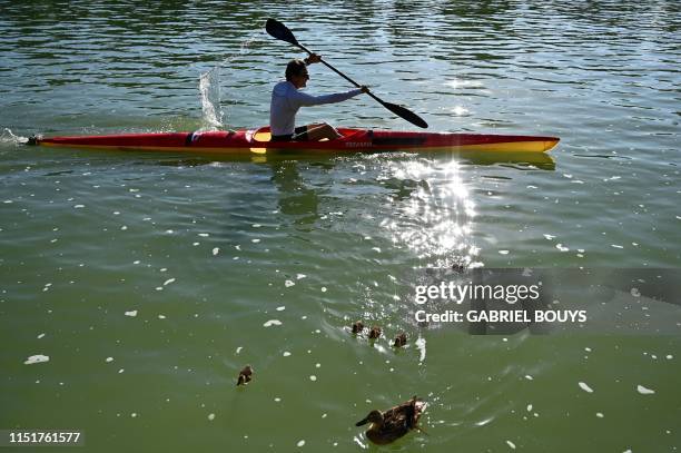 Man rows on the pond of the Retiro Park in downtown Madrid on June 25, 2019. - 'Parque del Buen Retiro' , or commonly 'El Retiro' is one of the...