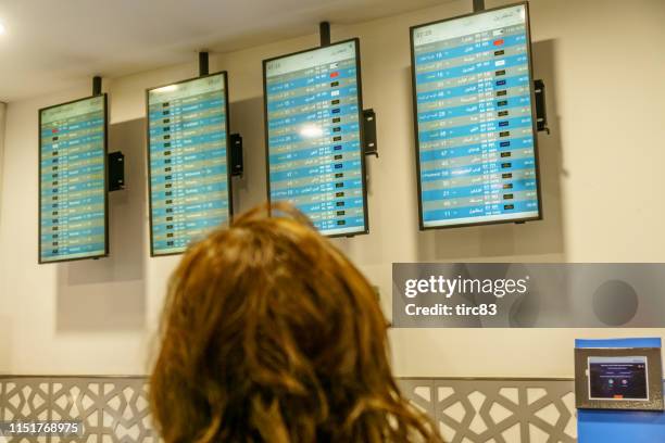 woman checking airport departure board - abu dhabi airport stock pictures, royalty-free photos & images