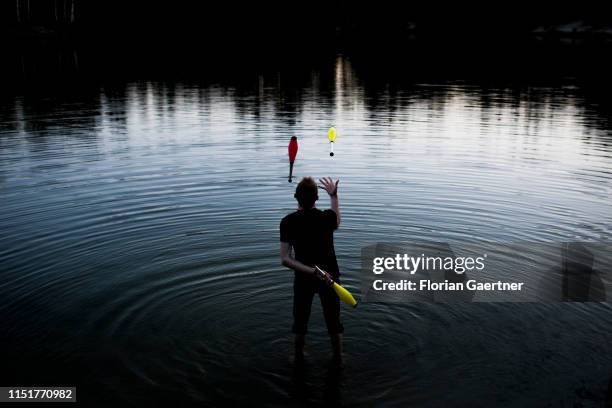 Man juggling three clubs in a lake is pictured on June 23, 2019 in Niesky, Germany.