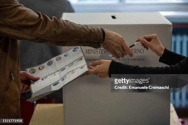 Polling station official gives a pencil and a ballot to a man during the European Parliamentary election at a polling station on May 26, 2019 in...