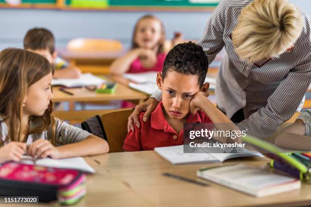 female teacher consoling crying black student in the classroom. - teacher crying stock pictures, royalty-free photos & images
