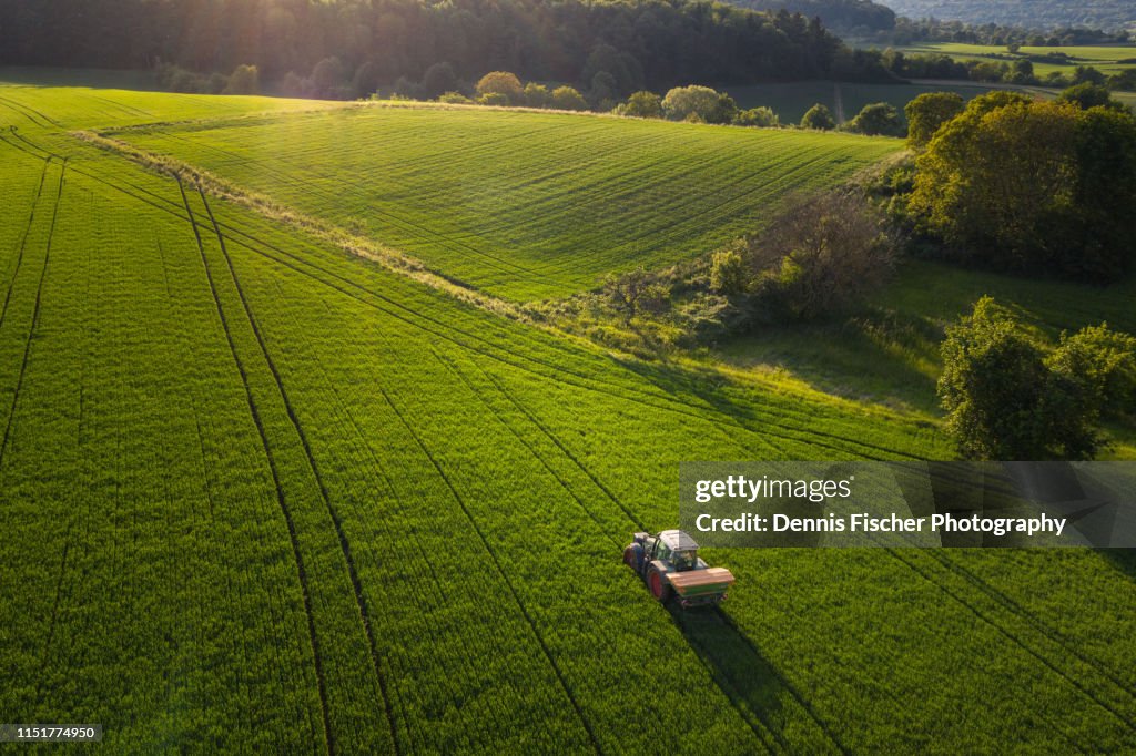 A farmer tills a field with his tractor