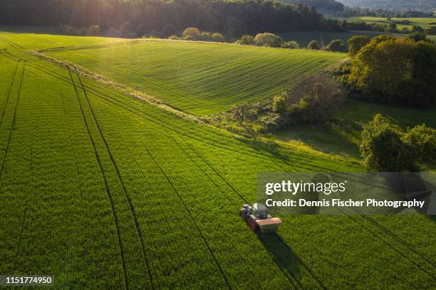 a farmer tills a field with his tractor - cultivated land fotografías e imágenes de stock