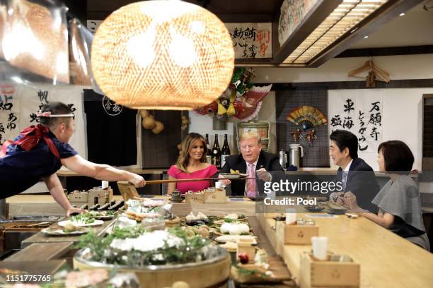 President Donald Trump, center, is served a baked potato with butter while sitting at a counter with First Lady Melania Trump, second left, Shinzo...