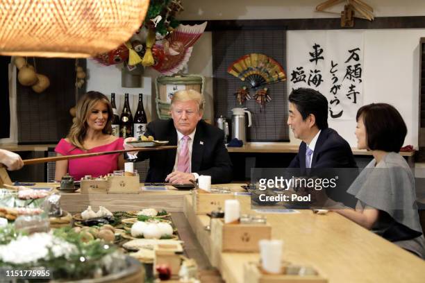 President Donald Trump, second left, is served a baked potato with butter while sitting at a counter with First Lady Melania Trump, left, Shinzo Abe,...