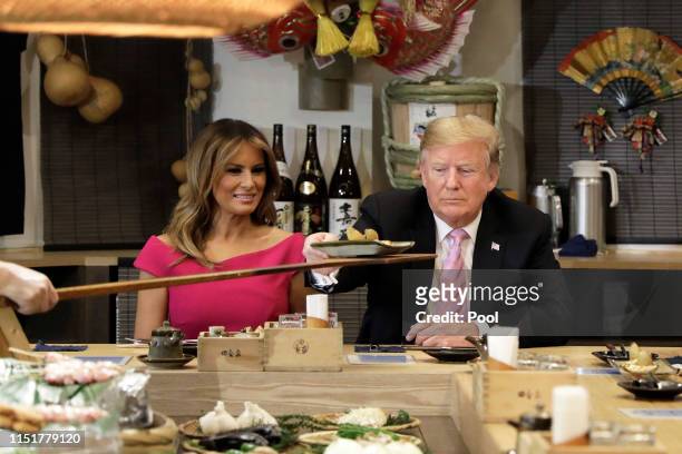President Donald Trump is served a baked potato with butter while sitting at a counter with First Lady Melania Trump, Shinzo Abe, Japan's Prime...