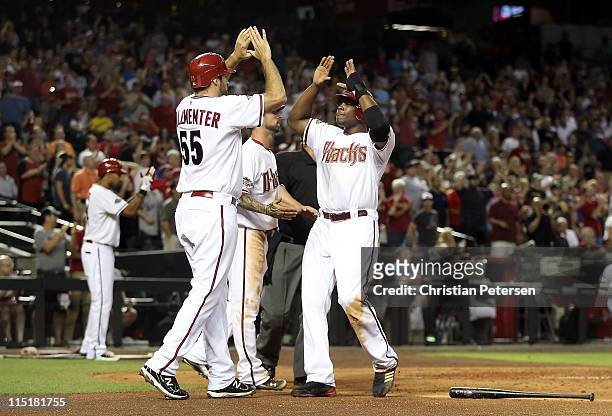 Justin Upton of the Arizona Diamondbacks high-fives teammates Josh Collmenter and Ryan Roberts after all scored on a triple hit by Stephen Drew...