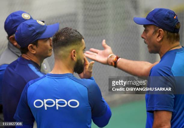 India's captain Virat Kohli listens as India's head coach Ravi Shastri talks during a training session at Old Trafford in Manchester, northwest...