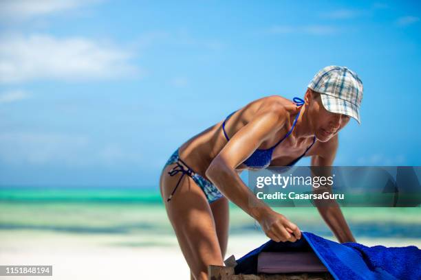 donna adulta che mette l'asciugamano sulla sedia a sdraio durante le vacanze al mare - sedia a sdraio foto e immagini stock