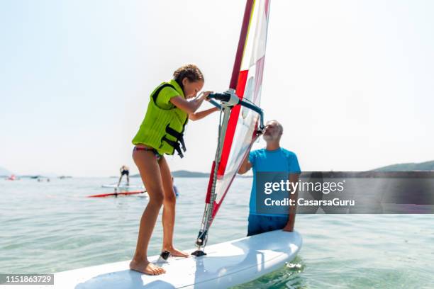 little girl receiving her first windsurf lessons - windsurfing stock pictures, royalty-free photos & images