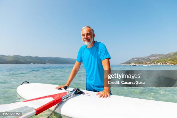 windsurflehrer porträt neben dem windsurfbrett - windsurfbrett stock-fotos und bilder